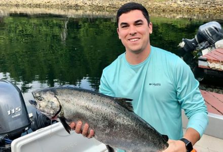 Happy young man holding his salmon catch