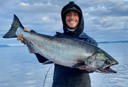 Man smiling as he holds his big salmon