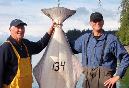 Two guests stand next to their 134 pound halibut.