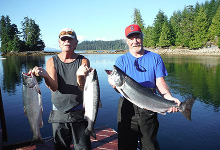 Two guests hold three salmon.
