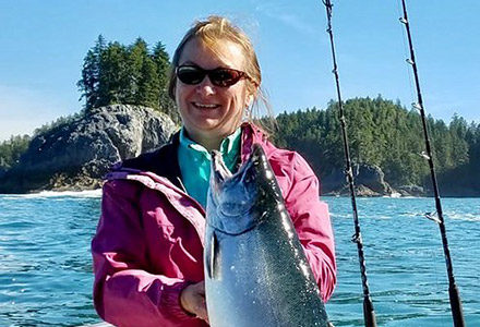 Guest holds up her king salmon catch on the fishing boat.