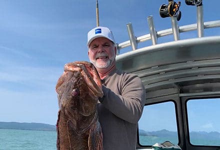 Guest hold his massive ling cod on the boat.