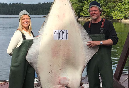 Guest couple poses with their hanging 404 pound halibut!