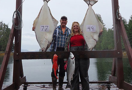 Guest couple poses with their catch of the day including a 77 and 49 pound pair of halibut.
