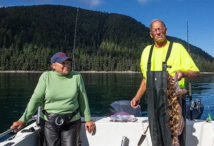 Guest holds a large ling cod with his wife on one of the fishing boats.