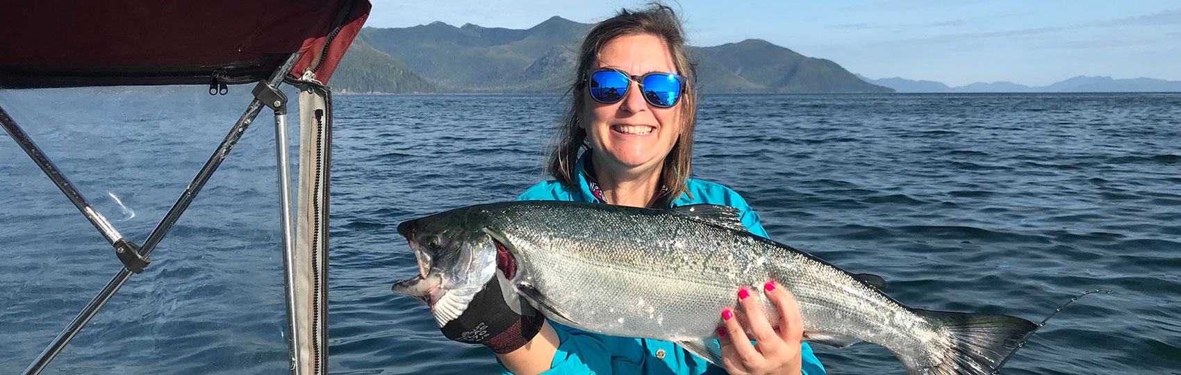 A woman holds up her king salmon catch.