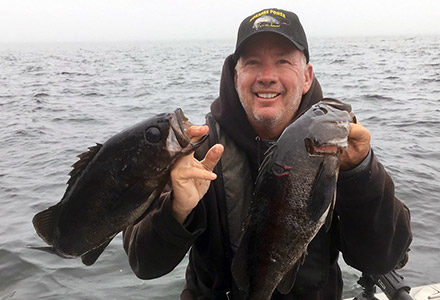 Guests hold two black rockfish.