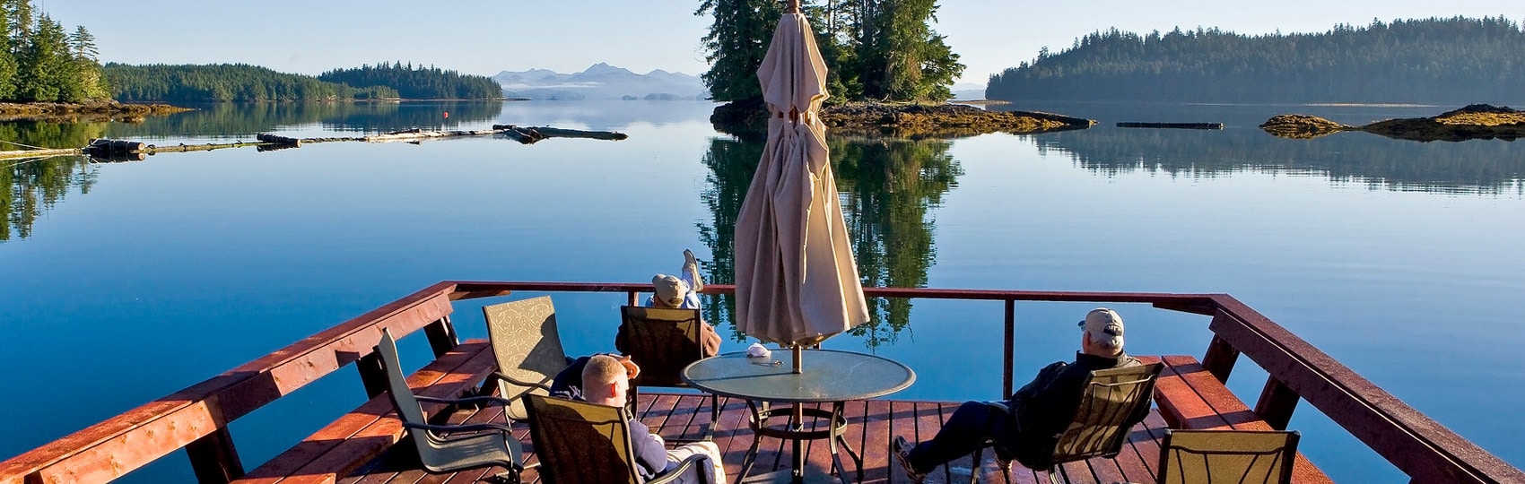 Guests enjoy the deck on a sunny day looking out over calm water.