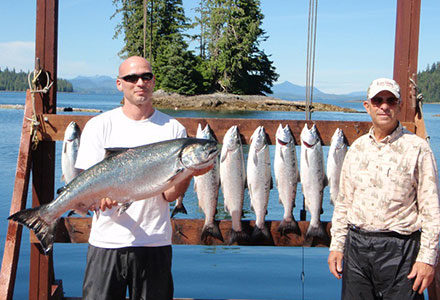 Guests pose with salmon catch in the sunshine on the dock.