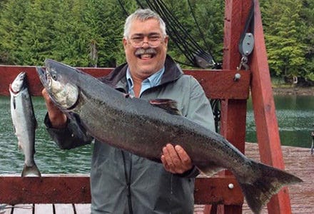 Guests hold his big king salmon catch on the dock.