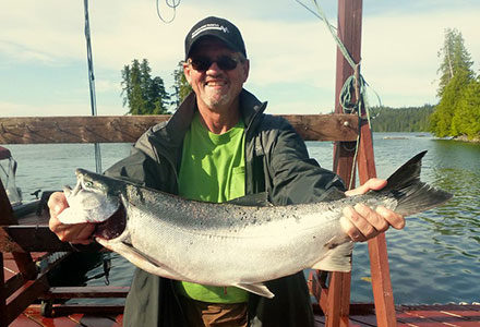 Guest hold his king salmon catch on the dock