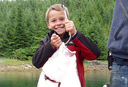Young boy poses with halibut catch.