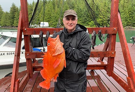 Guest holds his bright yelloweye rockfish on the dock.