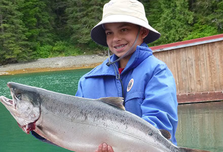 Young boy guest poses with his salmon catch.