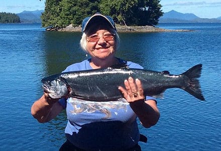 Woman holds a nice silver salmon catch.