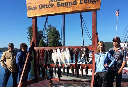 Guests pose with their catch on the Sea Otter Sound Lodge sign.