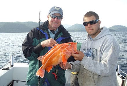 Two guests hold a nice yelloweye rockfish on the fishing boat.