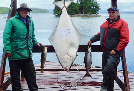Two guests pose with their 103 pound halibut catch.
