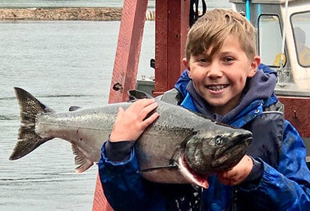 Small guest holds king salmon catch.