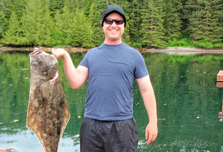 Guest holds a halibut on the dock.
