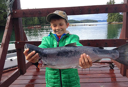 Young boy proudly holds his king salmon.