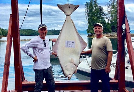 Two guests pose with their 127 pound halibut.