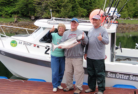Three guests pose with king salmon in front of the lodge fishing boat.