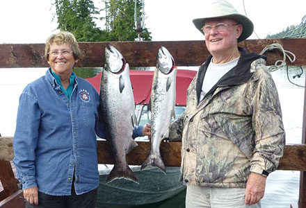 Guest couple stand next to their hanging king salmon catch.