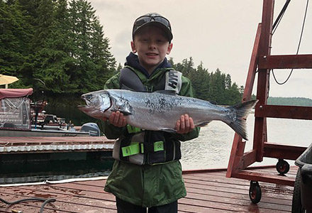 Young boy holds a salmon.