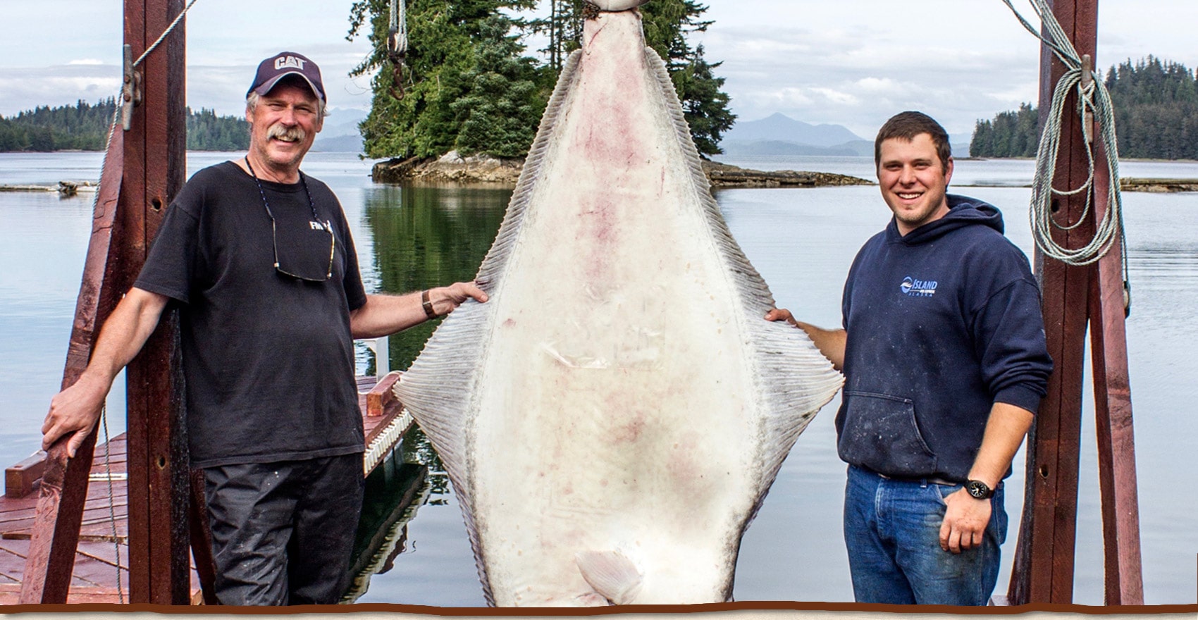 Guests at the lodge pose with a huge halibut catch on th lodge's dock.