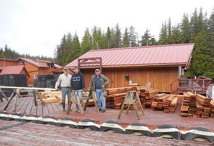 The Start Up Crew works on the dock with lumber stacked up behind them.
