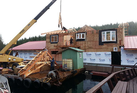 A crane places a roof truss on the lodge.