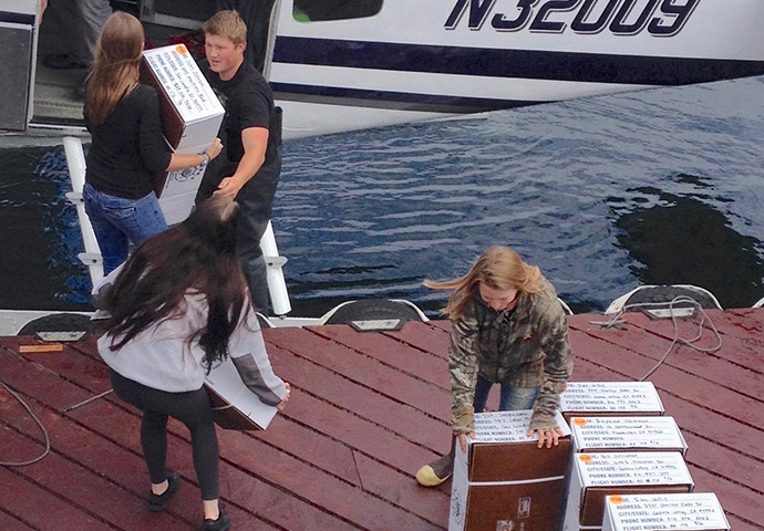 The crew loads the float plane with fish boxes.